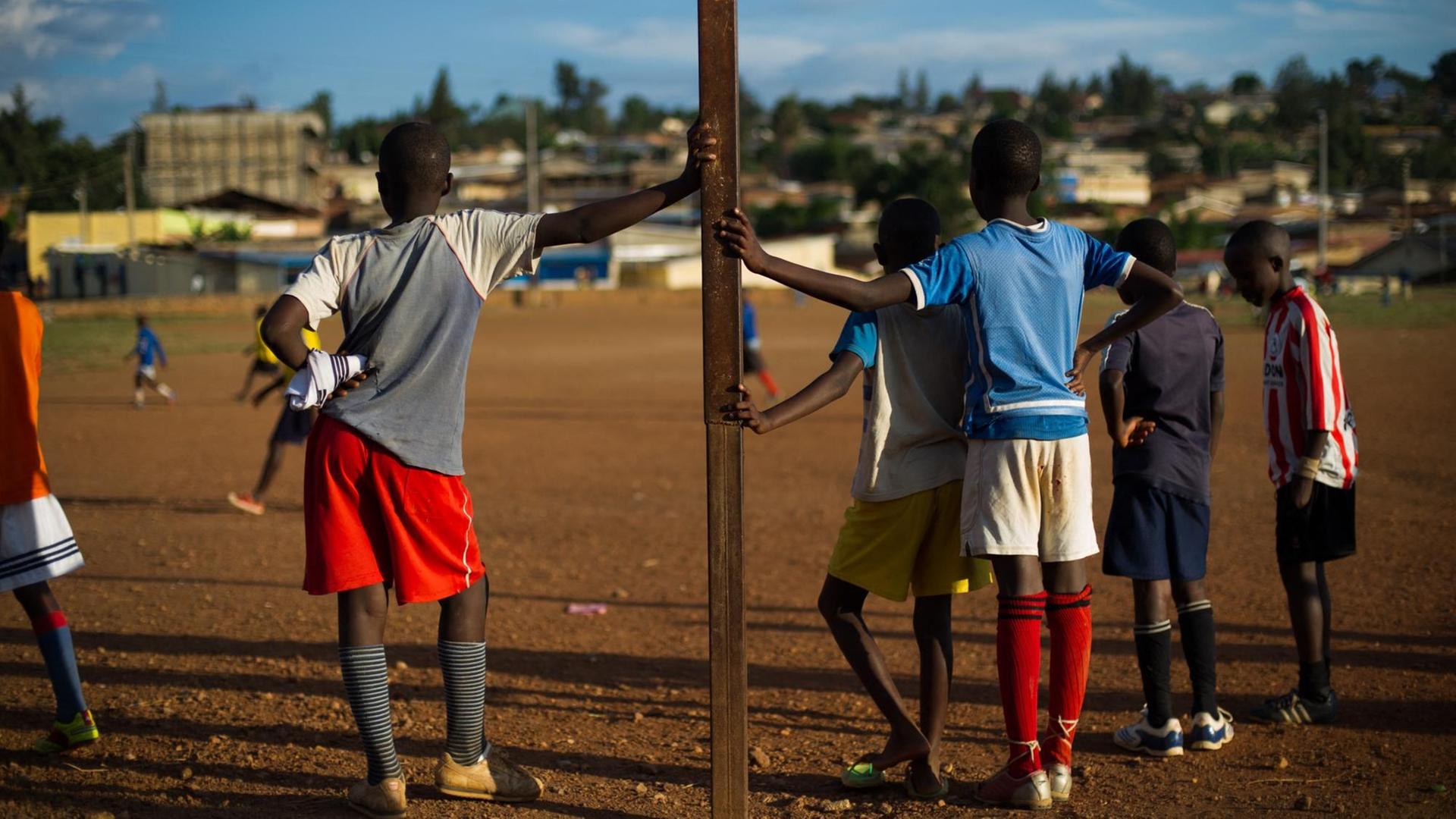 Mehrere Kinder stehen während eines Fußballspiels an den Torpfosten gelehnt.