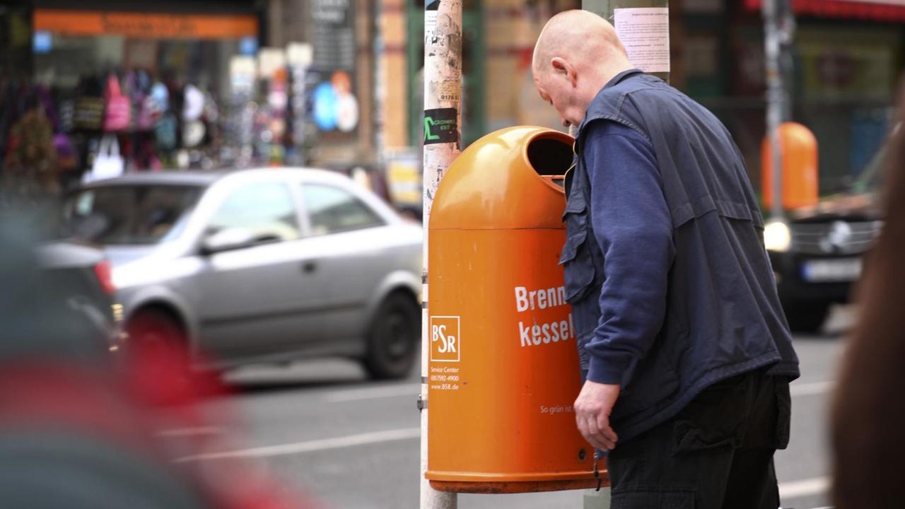 Ein Mann sucht in Berlin in einem Papierkorb nach Pfandflaschen oder Pfanddosen (Symbolbild)