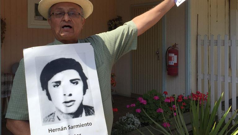 Victor Sarmiento hält ein Plakat seines Bruders Hernán Sarmiento, dessen Spur sich 1974 in der damaligen Colonia Dignidad verlor.
