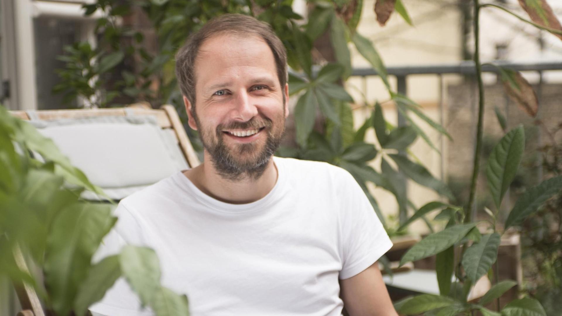 Christian Kroll, Gründer der grünen Suchmaschine "Ecosia" sitzt mit Laptop im Freien.