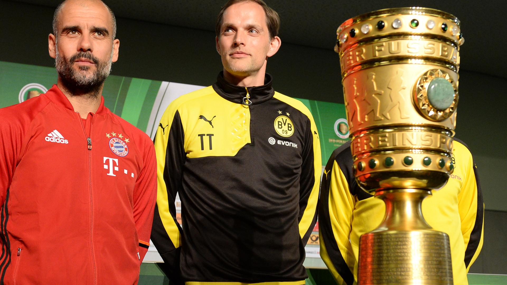 Trainer Pep Guardiola (l.) vom FC Bayern München und BVB-Trainer Thomas Tuchel stehen im Olympiastadion in Berlin neben dem DFB-Pokal.