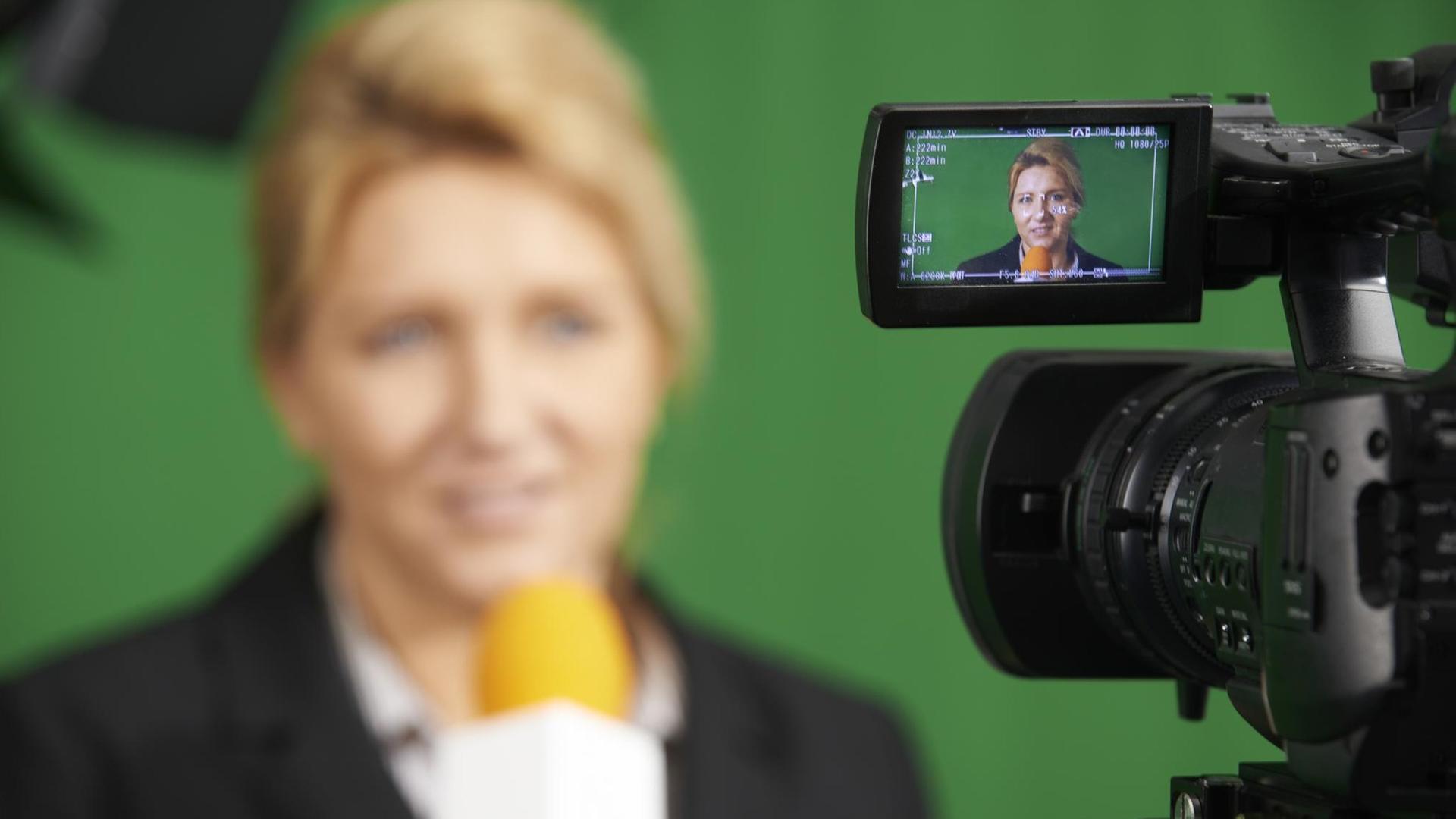 Moderatorin im Fernsehstudio durch die Anzeige einer Kamera gesehen (Symbolfoto).