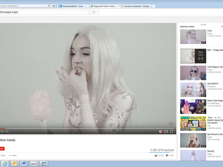 Ein Screenshot von Poppys YouTube Video "Poppy Eats Cotton Candy" - Poppy stopft sich Zuckerwatte in den Mund.