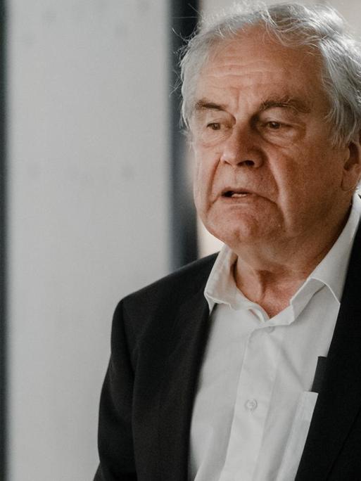 Frido Mann steht in nachdenklicher Pose in einem Gebäudeflur