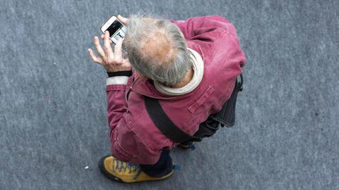 Ein Mann schaut mit gesenktem Kopf auf sein Smartphone