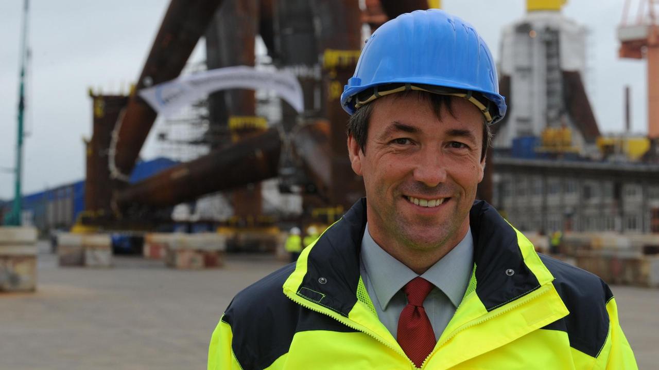 Der SPD-Bundestagsabgeordnete Joahann Saathoff steht mit blauem Helm und gelber Jacke auf dem Werftgelände der Nordseewerke in Emden (Niedersachsen).