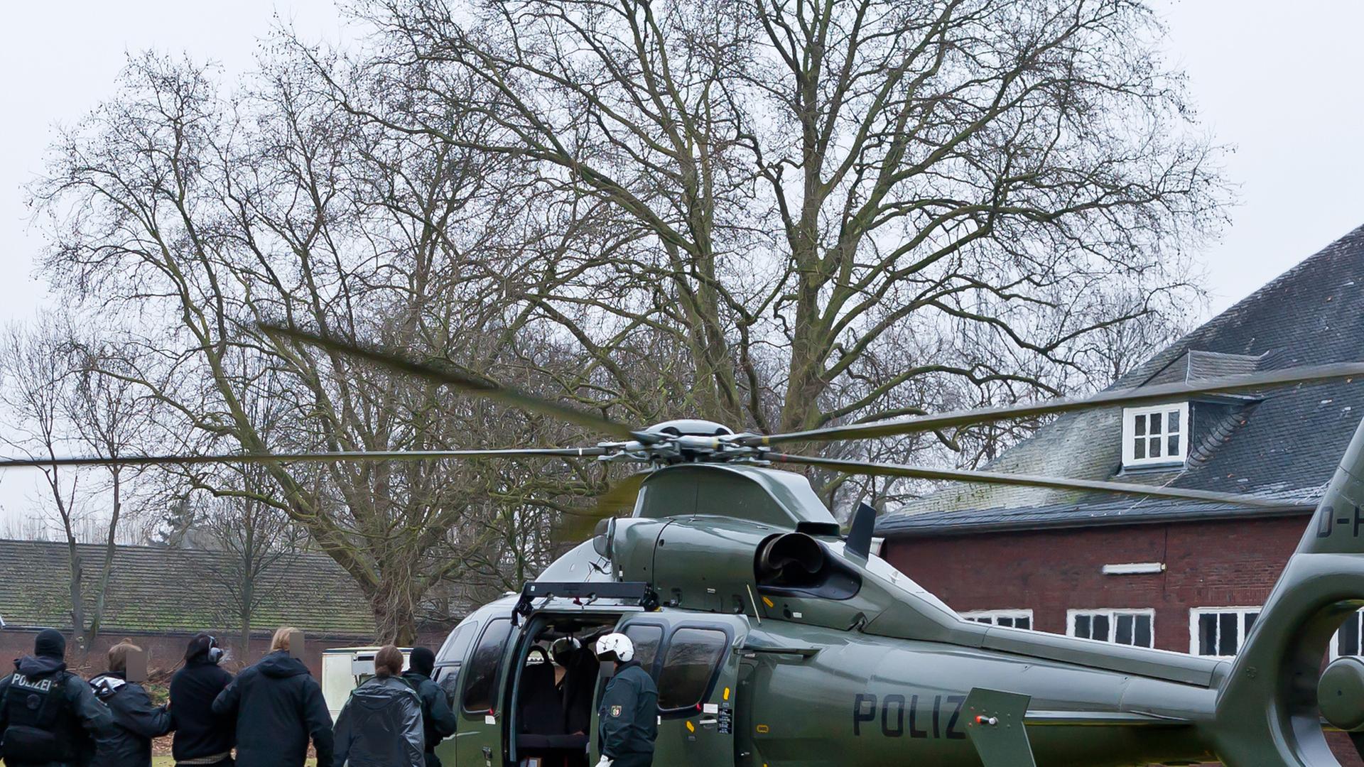 Polizisten führen in Mönchengladbach einen Terrorverdächtigen in Handschellen zu einem Hubschrauber.