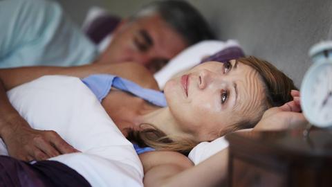 Eine Frau liegt mit Schlafproblemen im Bett.