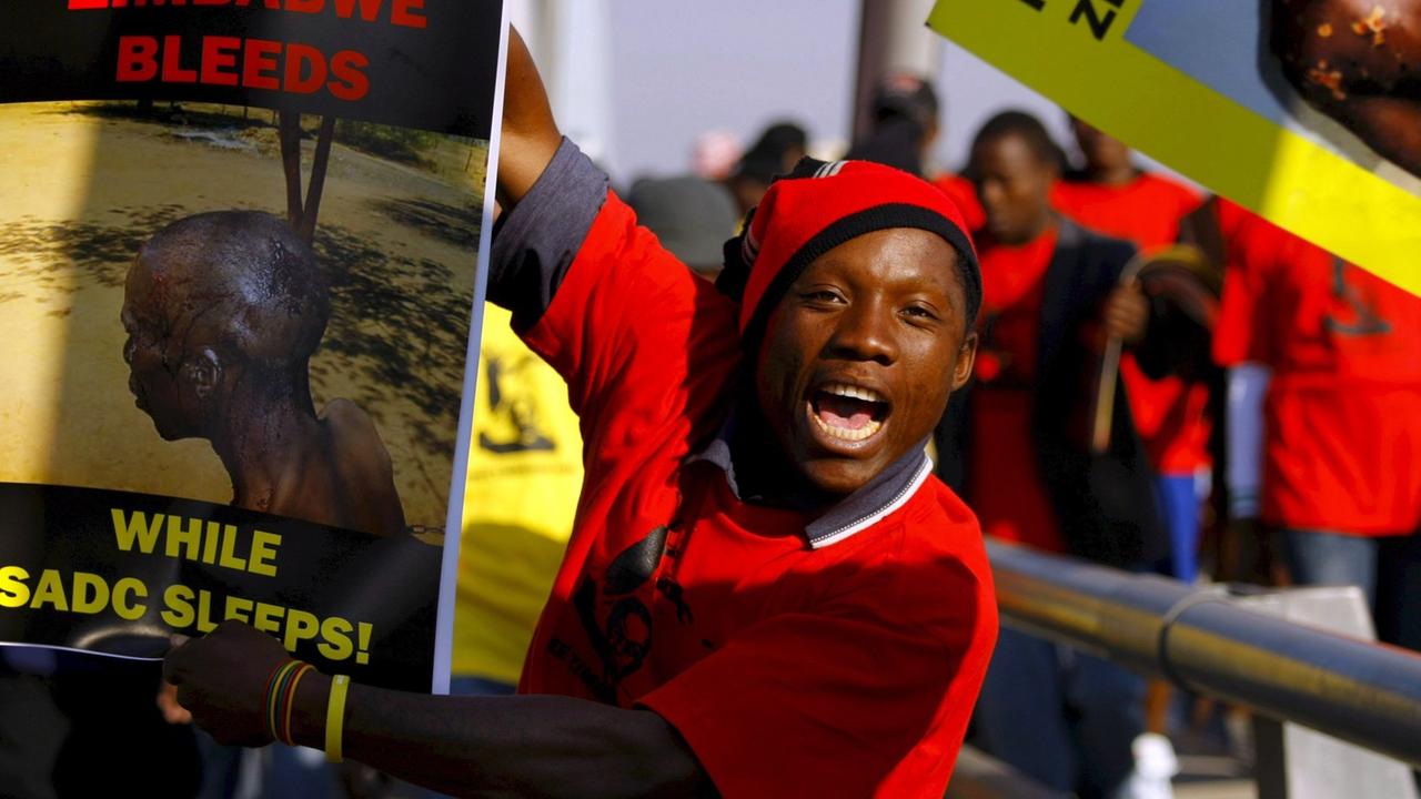 Demonstranten in Johannesburg, die Plakate mit Folter-Opfern hochhalten