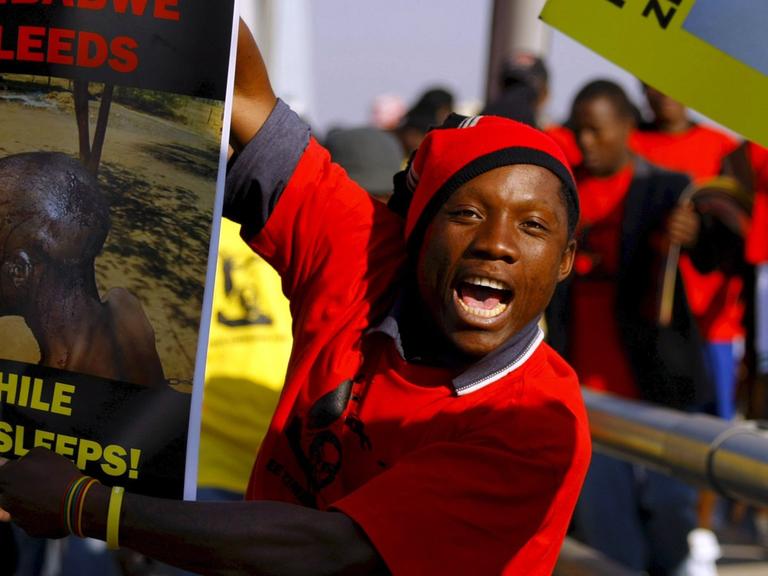 Demonstranten in Johannesburg, die Plakate mit Folter-Opfern hochhalten