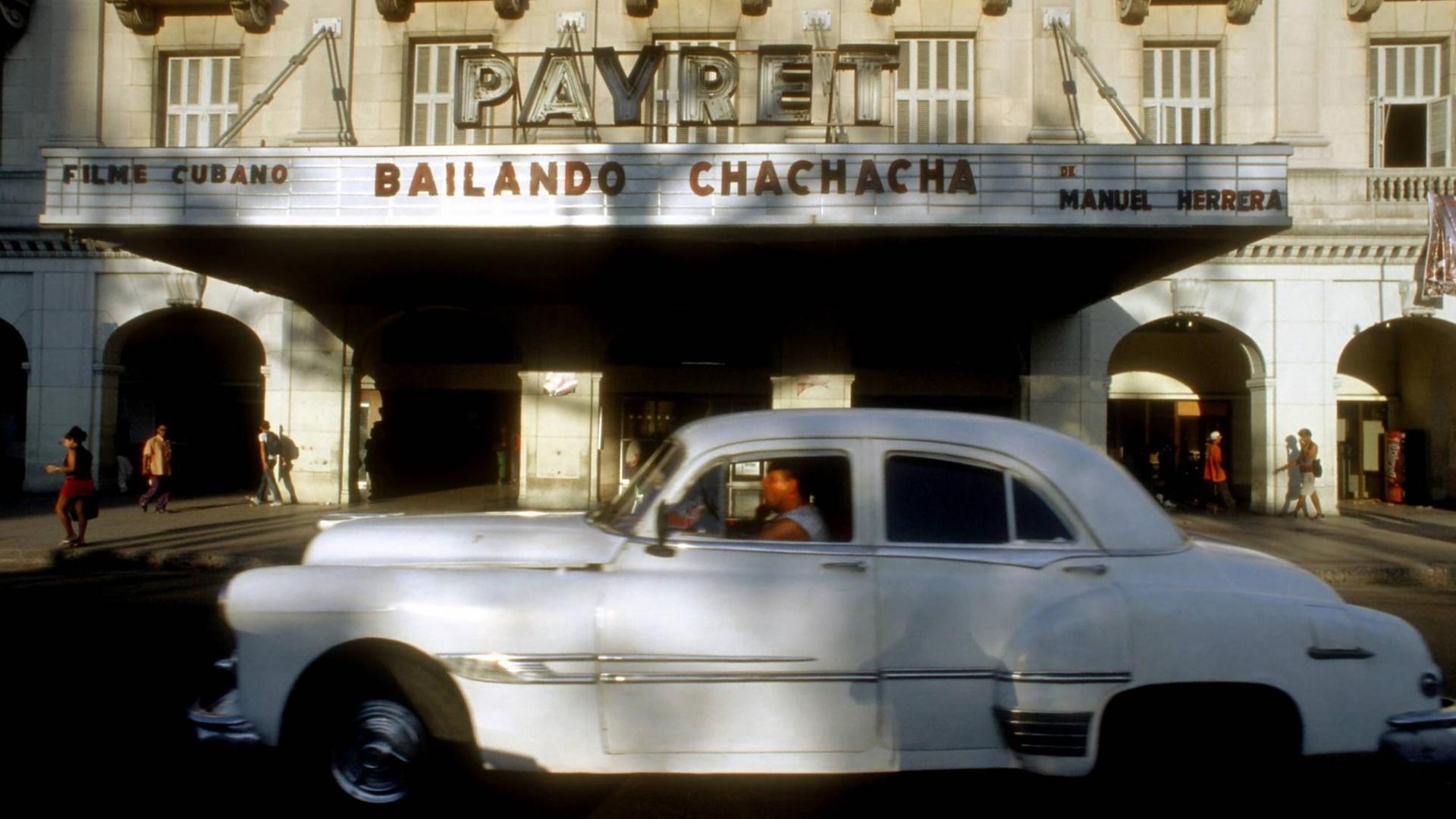 Ein Chevrolet der 1950er Jahre fährt an der Front des Cine Payret in Havanna vorrüber
