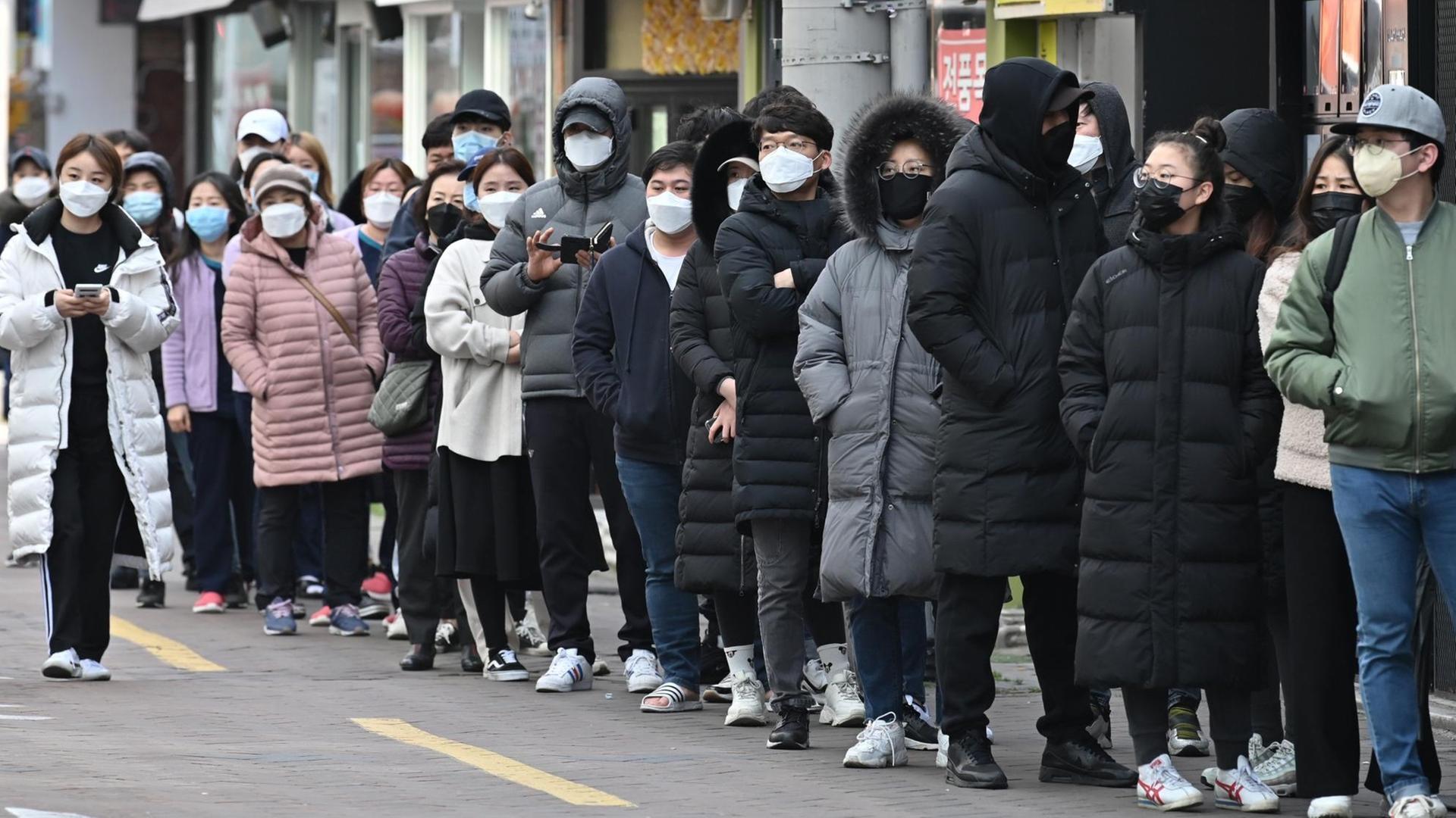 Menschen stehen vor einem Geschäft in Daegu Schlange, um Atemschutzmasken zu kaufen.