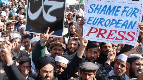 Demonstranten in Pakistan, die mit einem Plakat "Shame for European Press" gegen den Abdruck von Mohammed-Karikaturen in europäischen Medien protestieren (aufgenommen 2006).