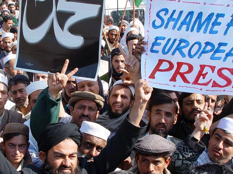 Demonstranten in Pakistan, die mit einem Plakat "Shame for European Press" gegen den Abdruck von Mohammed-Karikaturen in europäischen Medien protestieren (aufgenommen 2006).