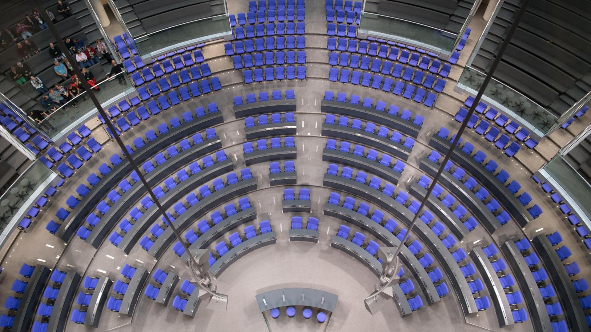 Eine Gruppe Besucher sitzt im Plenarsaal im Reichstag in Berlin.