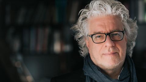 Der Dirigent Christoph Spering lächelt in die Kamera.