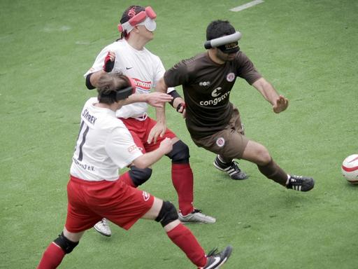 Lukas Smirek (l) und Sven Schwarze (M) vom MTV Stuttgart und Serdal Celebi von St. Pauli mit Ball auf Rasenplatz.