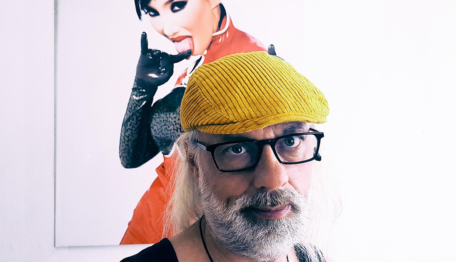 Porträtaufnahme des Konzertveranstalters Gunther Lorz mit gelber Mütze, im Hintergrund ein Bild