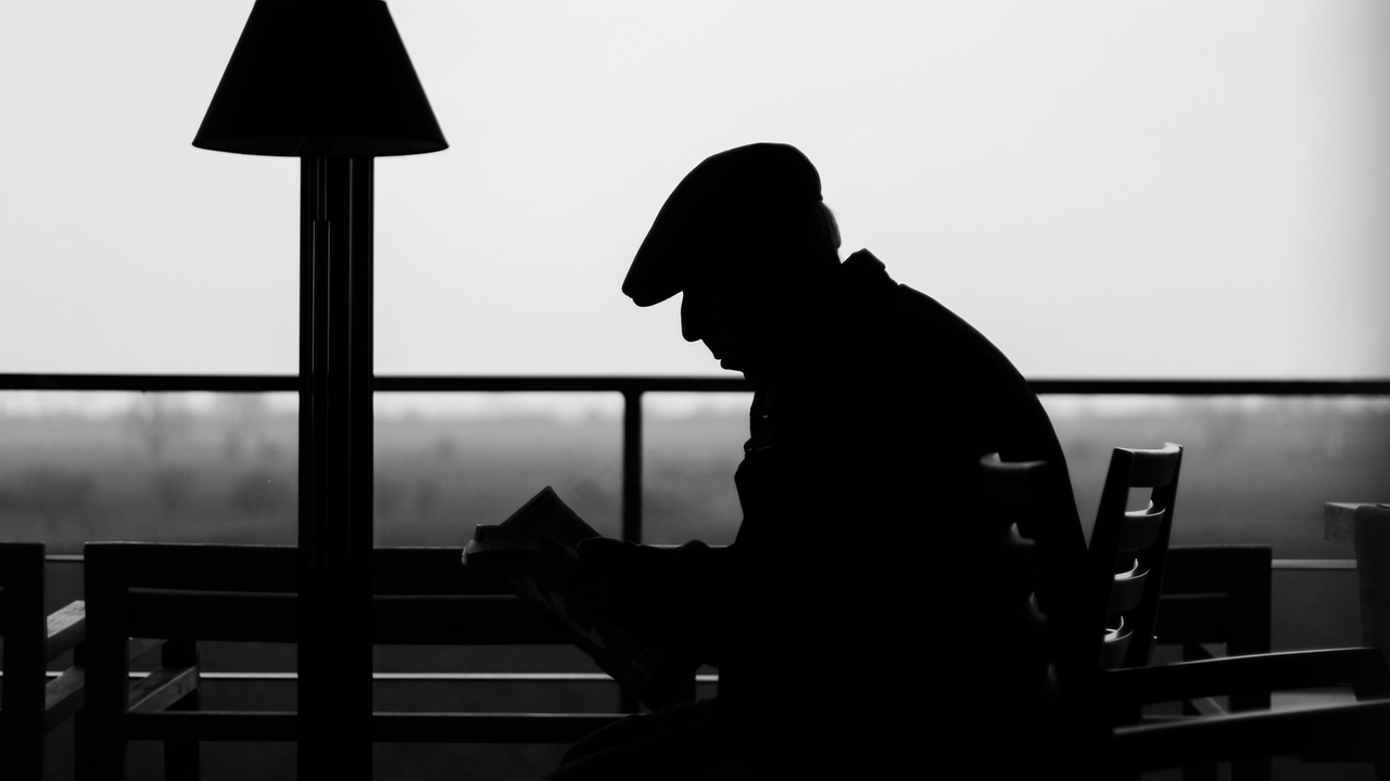 Die Silhouette eines ältereren Mannes im Gegenlichtz auf einer Terrasse.