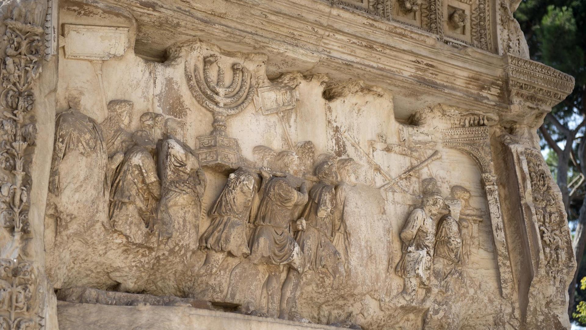 Darstellung des römischen Triumphzuges in der Innenwand des Titusbogens in Rom. Zu sehen sind römische Soldaten, jüdische Sklaven und die goldene Menora.