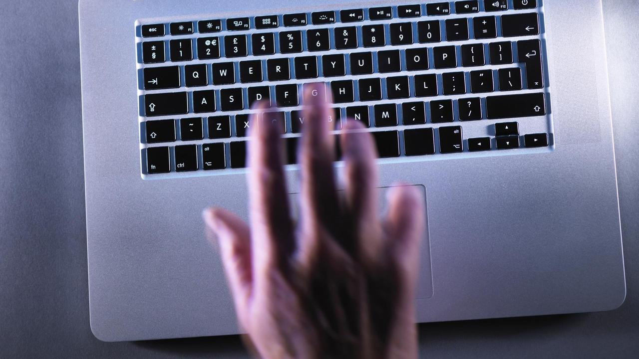 Eine Hand liegt auf einer Laptop-Tastatur Eine Hand liegt auf einer Laptop-Tastatur