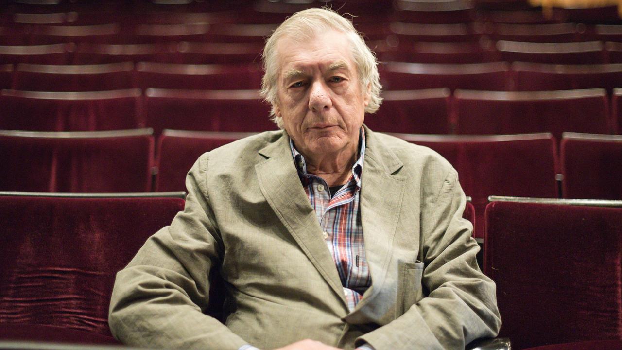 Regisseur Hans Neuenfels sitzt in einem Theatersaal.