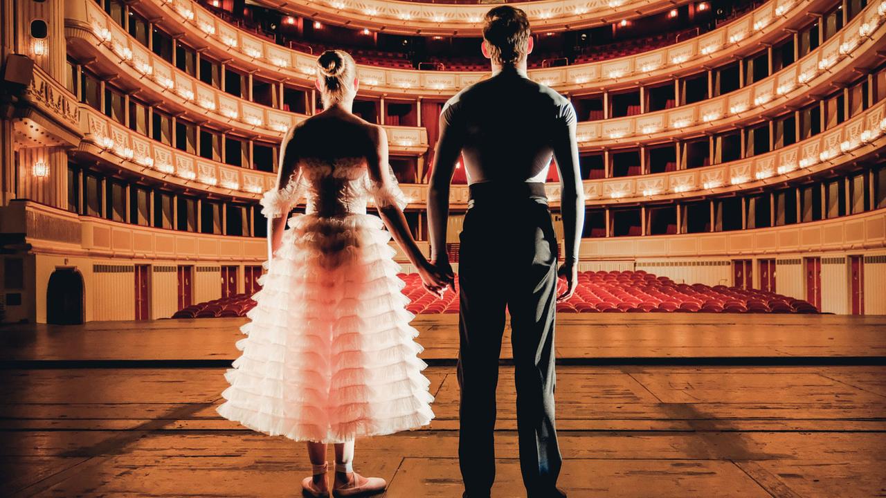 Eine Ballerina und ein Balletttänzer blicken von der Bühne in den Saal der Wiener Staatsoper, der 2.300 Zuschauerplätze hat.