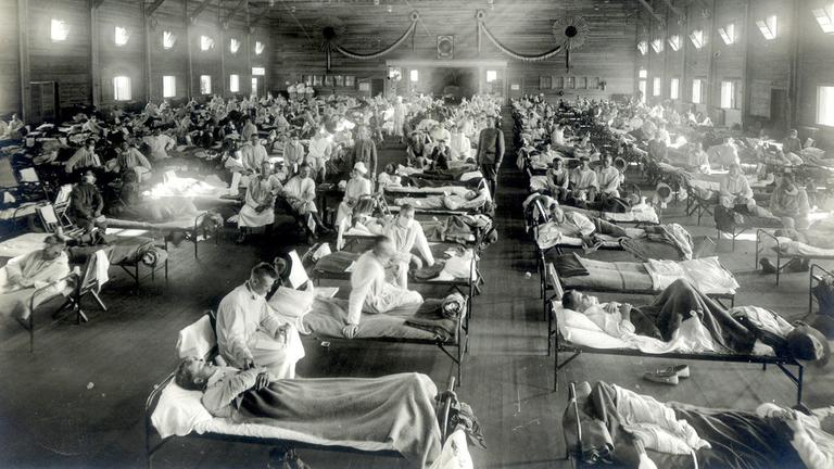 Patienten, die an der Spanischen Grippe erkrankt sind, liegen in Betten eines Notfallkrankenhauses im Camp Funston der Militärbasis Fort Riley in Kansas (USA) (Aufnahme von 1918). 