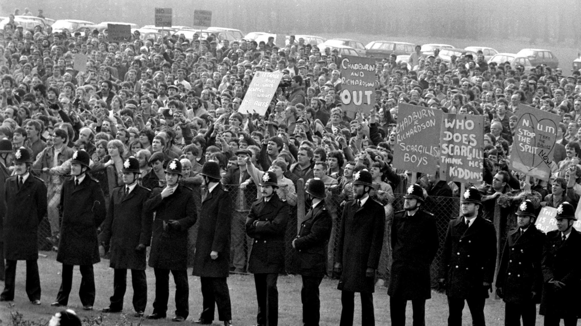 Steikende Bergarbeiter demonstrieren am 1. Mai 1984 im englischen Nottinghamshire gegen die Schließlung von Mienen. Vor ihnen steht eine Reihe von Polizisten.