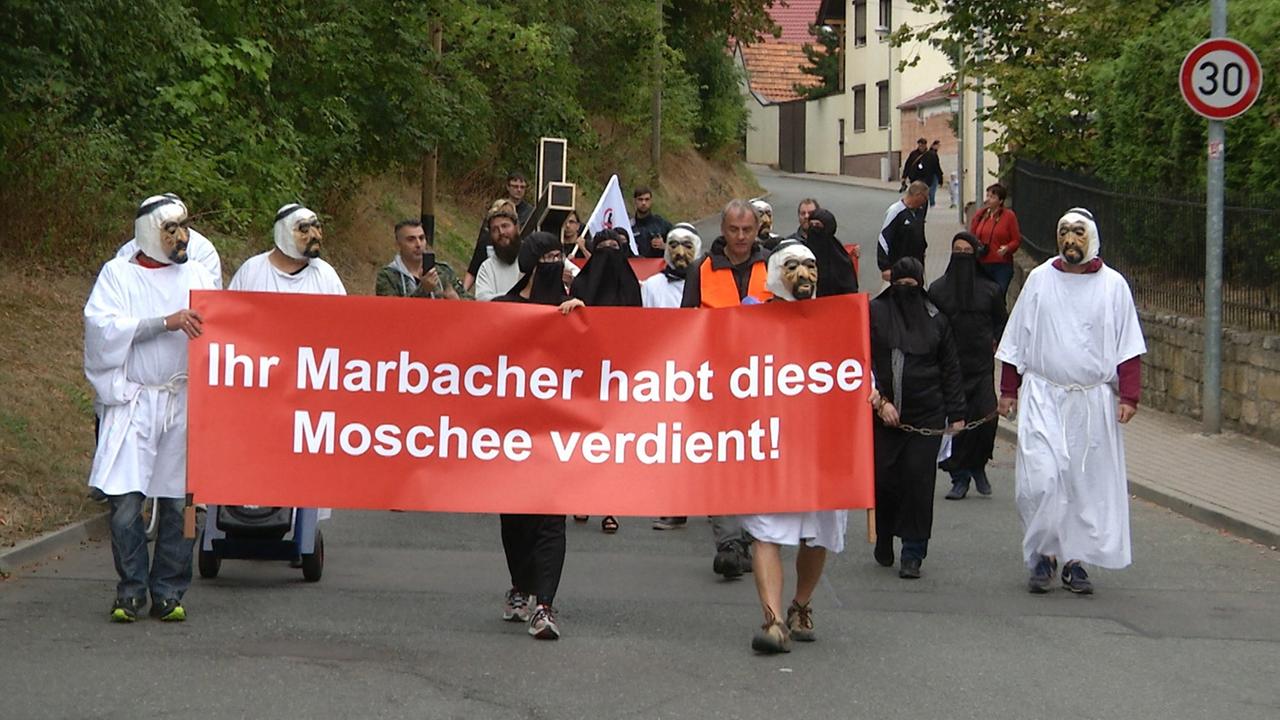 Mit einem Plakat "Ihr Marbacher habt diese Moschee verdient" ziehen Gegner des umstrittenen Moscheebaus in Erfurt-Marbach am 02.09.2018 durch den Ortsteil der Landeshauptstadt.