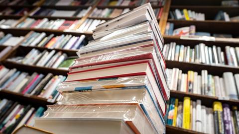 Ein Stapel neuer Bücher liegt auf einem Verkaufstisch in einer Buchhandlung im Stadtteil Bornheim.