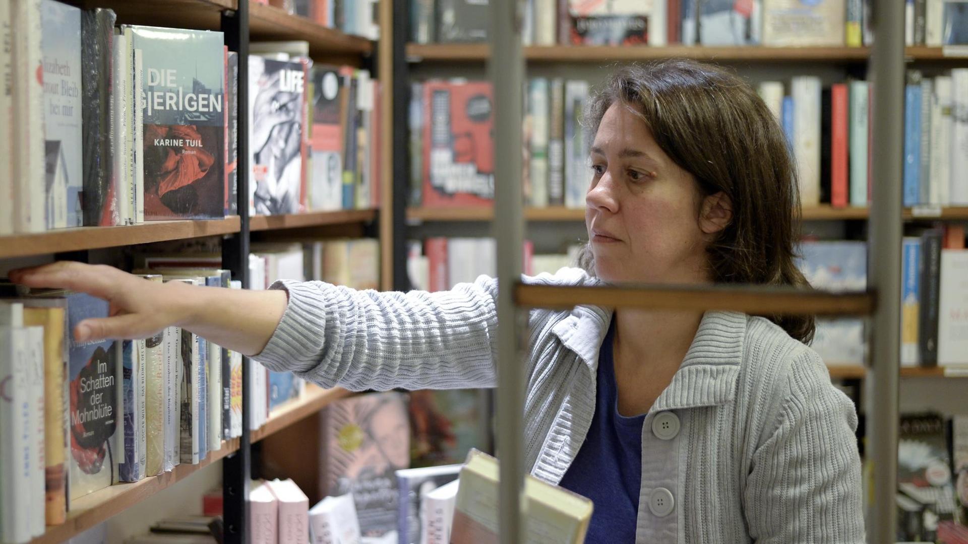 Die Buchhändlerin und Buchpreis-Jurorin Petra Hartlieb greift in ein Regal im Buchladen.
