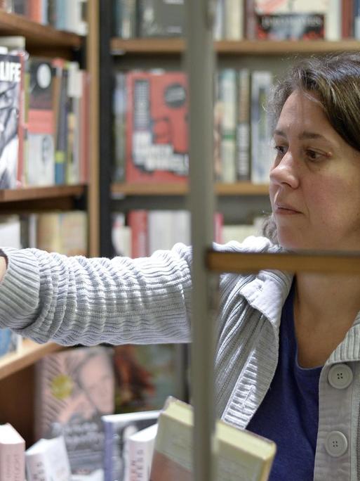 Die Buchhändlerin und Buchpreis-Jurorin Petra Hartlieb greift in ein Regal im Buchladen.