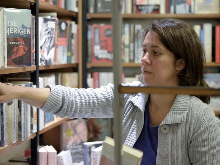 Die Buchhändlerin und Buchpreis-Jurorin Petra Hartlieb greift in ein Regal im Buchladen.