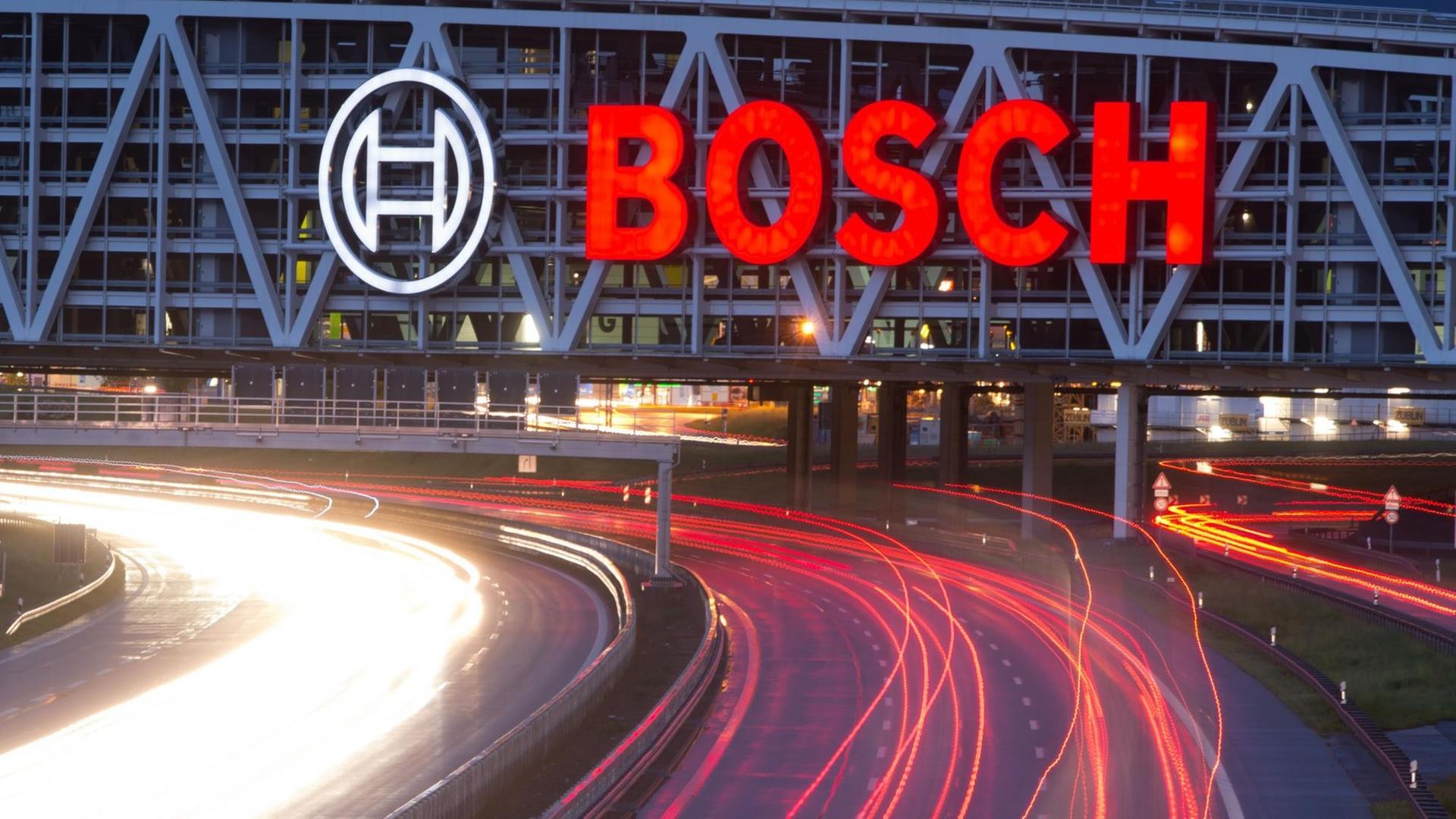 Autos fahren in Stuttgart unter einer Brücke mit Bosch-Logo hindurch.