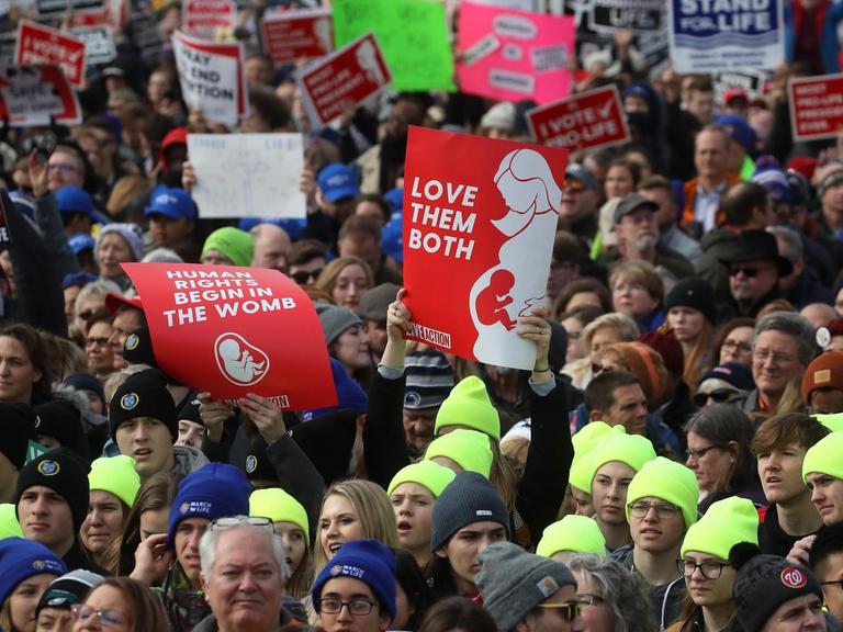 Blick auf eine Demonstration. Die Demonstrantinnen halten Banner, die sich gegen Abtreibung aussprechen.