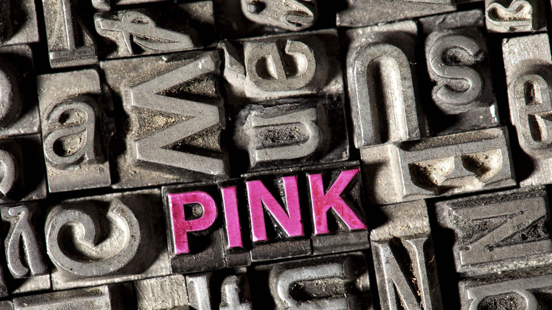 Setzkasten mit Bleilettern, darunter die Buchstaben des Wortes "pink" in rosa