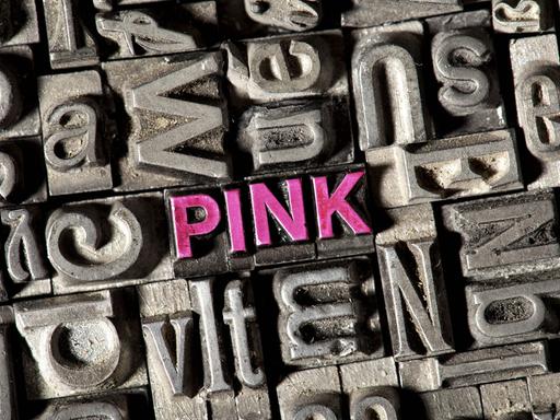 Setzkasten mit Bleilettern, darunter die Buchstaben des Wortes "pink" in rosa