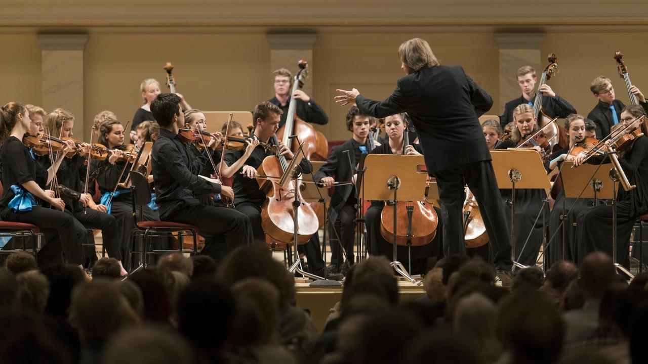 Orchester spielt unter der Anleitung des Dirigenten 