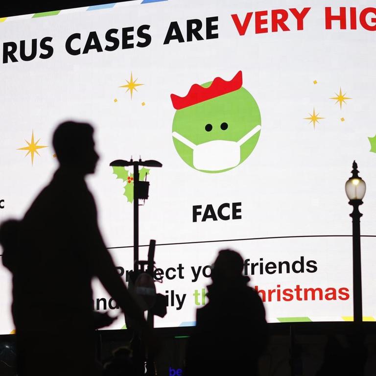 Fußgänger in London laufen an einer digitalen Anzeigentafel vorbei, auf der "Coronavirus-Fälle in London sehr hoch" steht