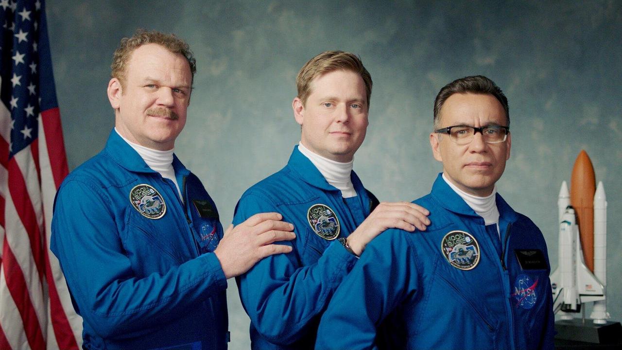 Im Still aus "Moonbase 8" posieren die drei Protagonisten in blauen Overalls für ein offizielles Porträt vor der US-Flagge.