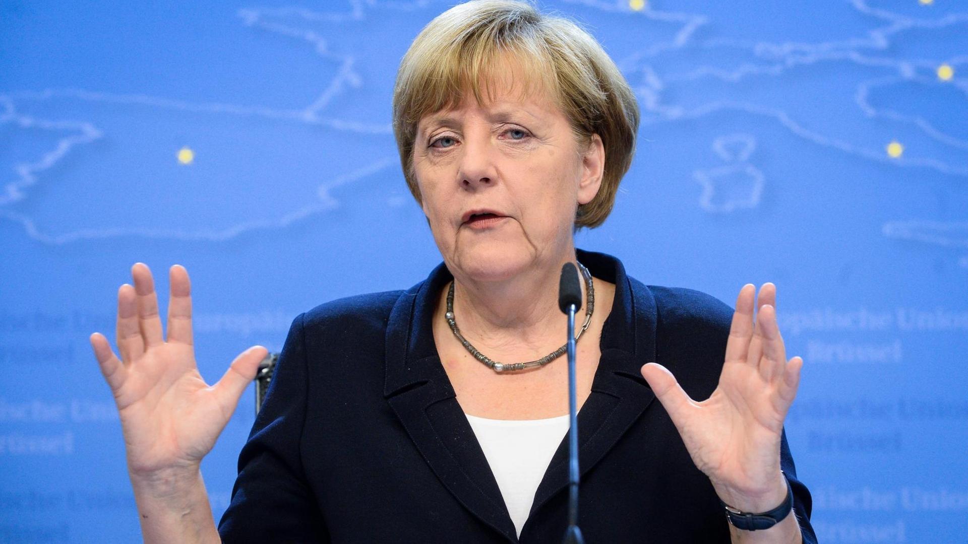 Angela Merkel spricht an einem Rednerpult und gestikuliert mit den Händen.