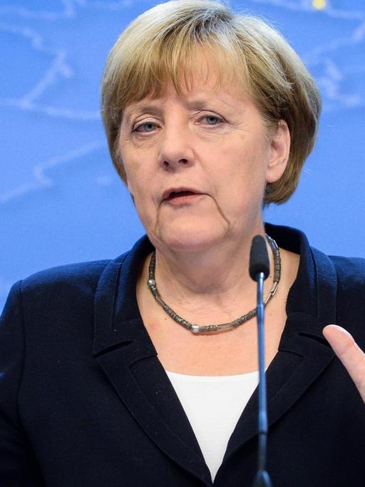 Angela Merkel spricht an einem Rednerpult und gestikuliert mit den Händen.