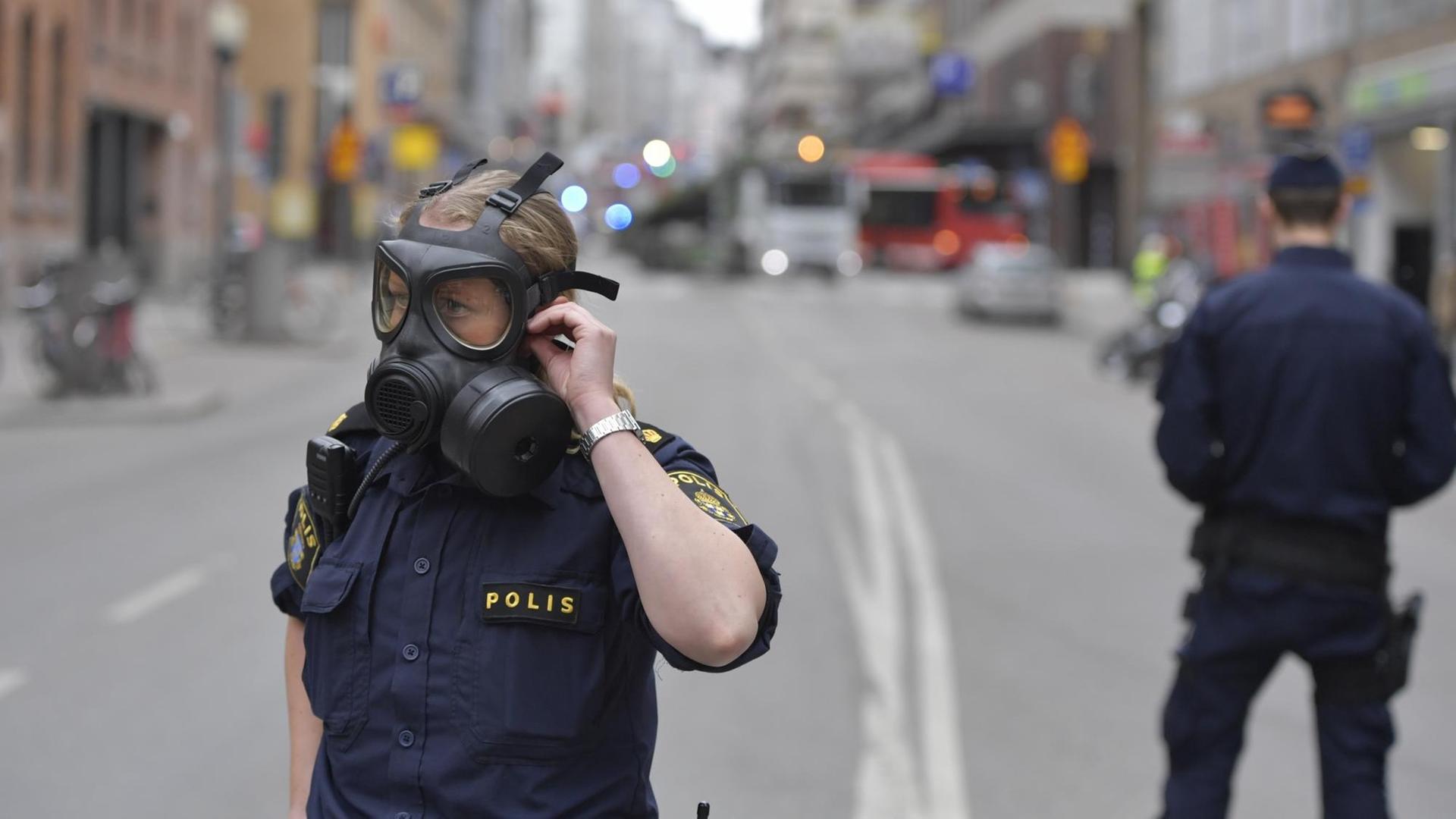 Polizisten stehen in Schutzkleidung in der Nähe des Anschlagsortes in Stockholm.