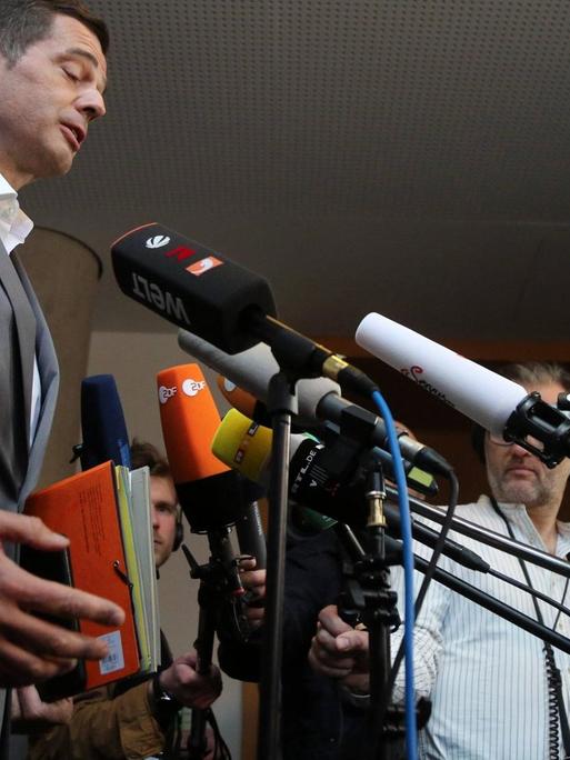 Thüringens CDU-Fraktionschef Mike Mohring steht links vor vielen Mikrofonen von Journalisten und hält eine rote Mappe in der Hand