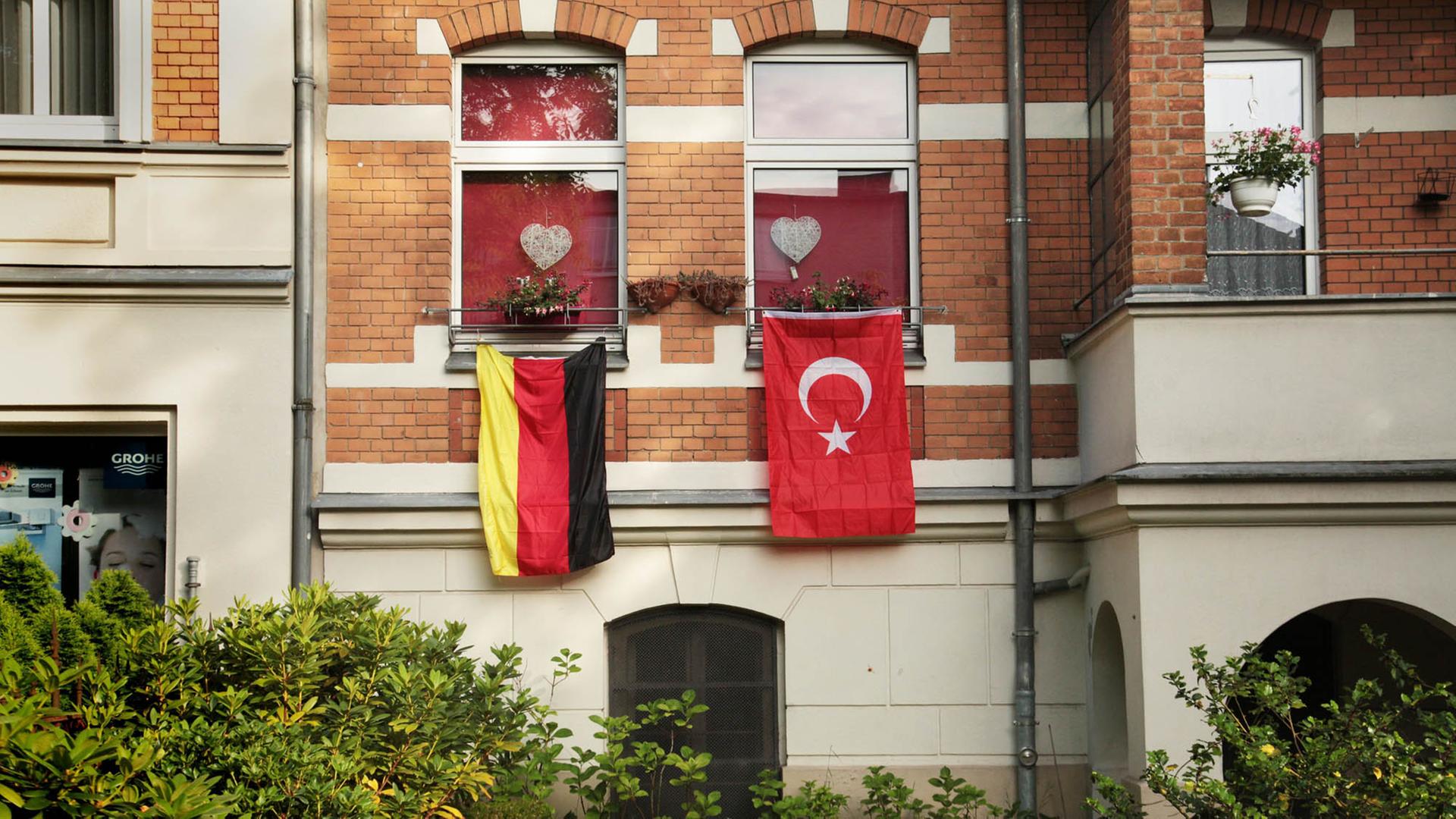 Eine rote, türkische Fahne mit dem Halbmond und dem Stern hängt während der Fußball-EM 2016 in Berlin an einem Haus neben der deutschen Flagge in Schwarz-Rot-Gold