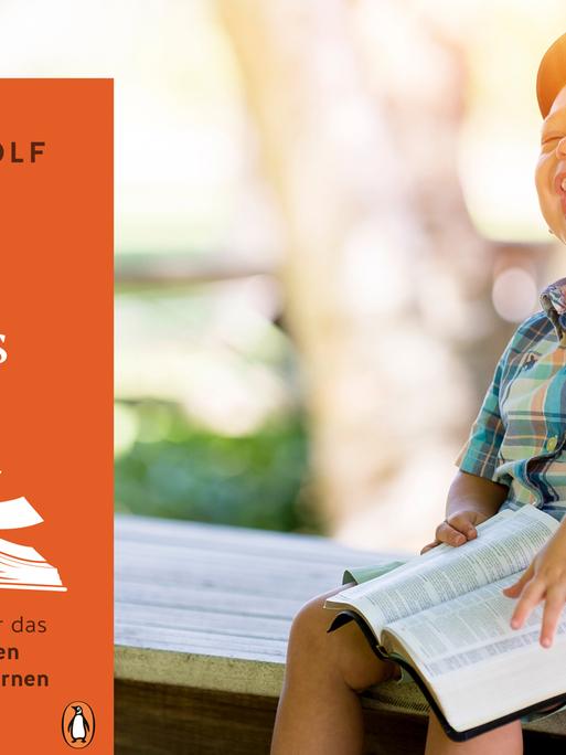 Ein kleiner Junge sitzt im Freien und freut sich beim Lesen.