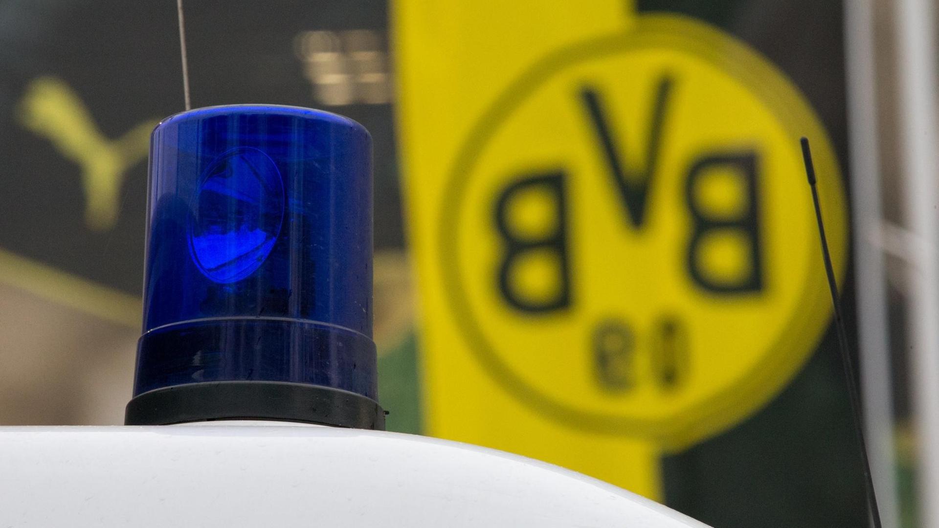 Das Blaulicht eines Polizeiwagens vor einer Fahne mit dem BVB-Logo.