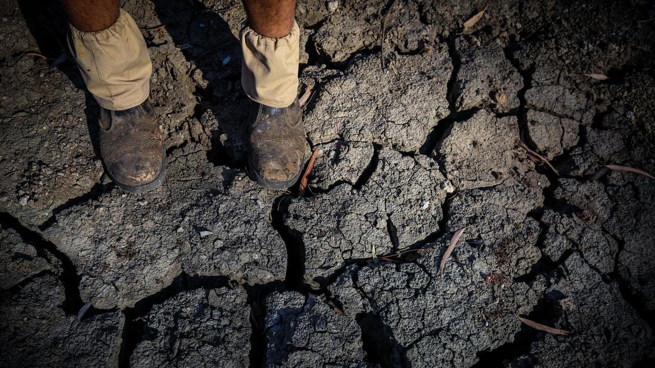 Die Füße eines Landwirts stehten im ausgetrockneten Bett des Namoi-Flusses.