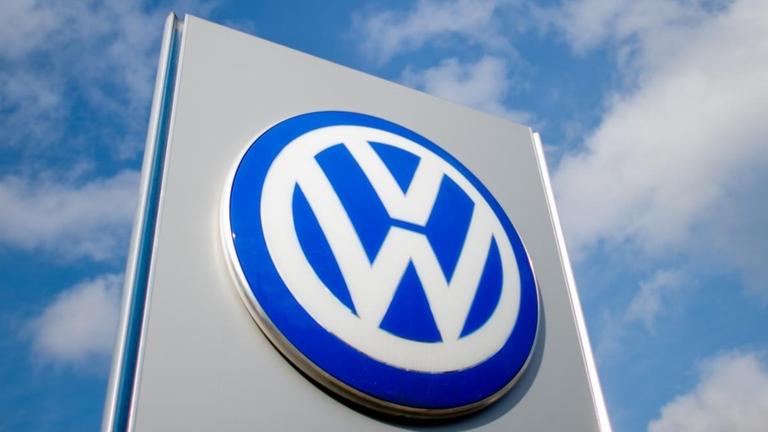 Ein Schild mit einem Volkswagen-Logo unter blauem Himmel mit weißen Wolken.